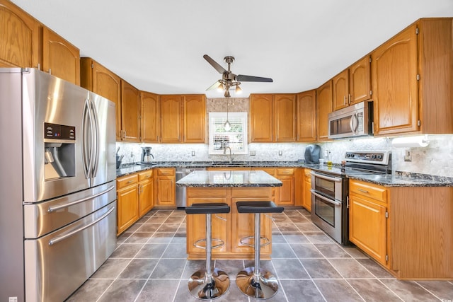 209 Chickasaw Ln, Myrtle Beach, SC 29579 - kitchen with stainless steel appliances, backsplash, a ceiling fan, a kitchen island, and dark stone countertops