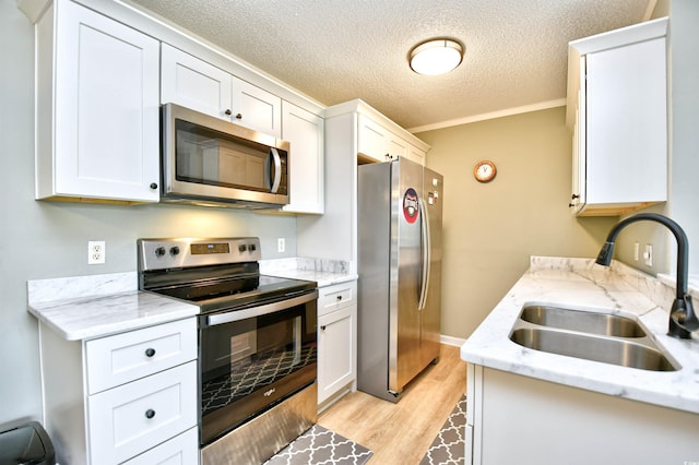 2187 Clearwater Dr Unit H, Surfside Beach, SC 29575 - kitchen with appliances with stainless steel finishes, light wood-type flooring, a textured ceiling, white cabinets, and ornamental molding