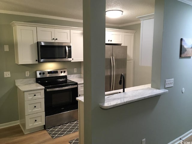 2187 Clearwater Dr Unit H, Surfside Beach, SC 29575 - kitchen featuring appliances with stainless steel finishes, ornamental molding, light wood-style flooring, white cabinetry, and light stone countertops