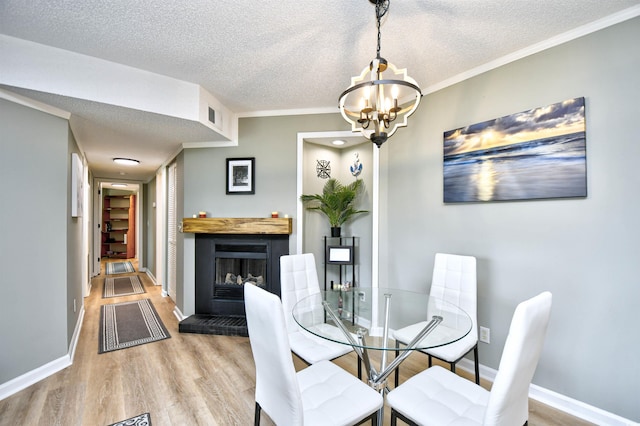 2187 Clearwater Dr Unit H, Surfside Beach, SC 29575 - dining area with light wood-style floors, a textured ceiling, a chandelier, a fireplace with raised hearth, and ornamental molding