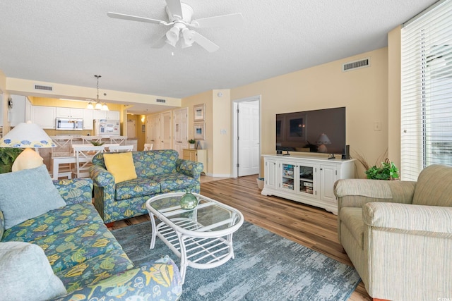5310 N Ocean Blvd Unit 7C, North Myrtle Beach, SC 29582 - living room featuring wood finished floors, healthy amount of natural light, a textured ceiling, a ceiling fan, and a chandelier