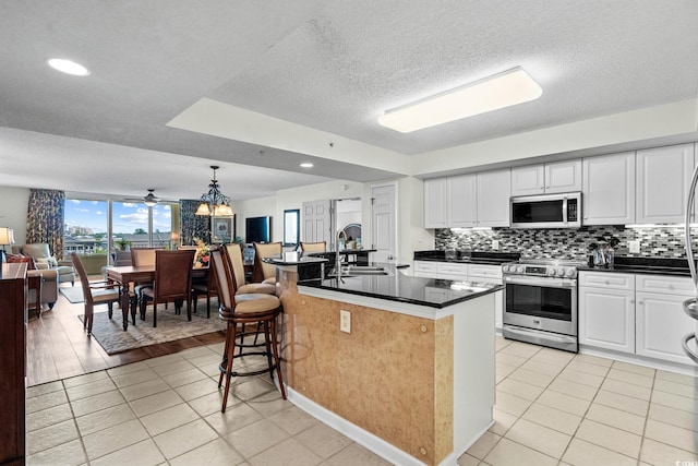 2151 Bridgeview Ct Unit 3-404, North Myrtle Beach, SC 29582 - kitchen featuring appliances with stainless steel finishes, open floor plan, dark countertops, light tile patterned floors, and tasteful backsplash