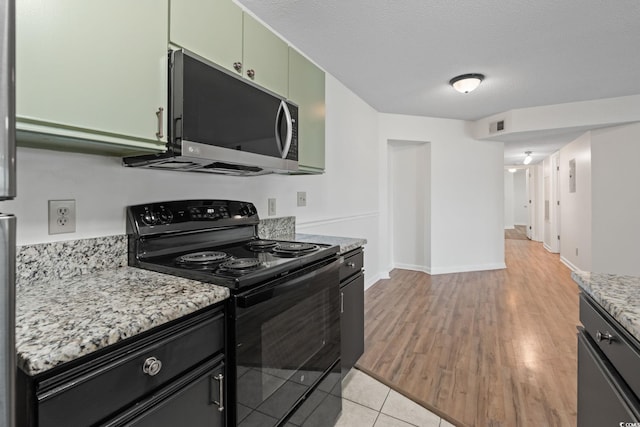 2122 Clearwater Dr Unit C, Surfside Beach, SC 29575 - kitchen with black range with electric stovetop, stainless steel microwave, light wood finished floors, green cabinets, and light stone countertops