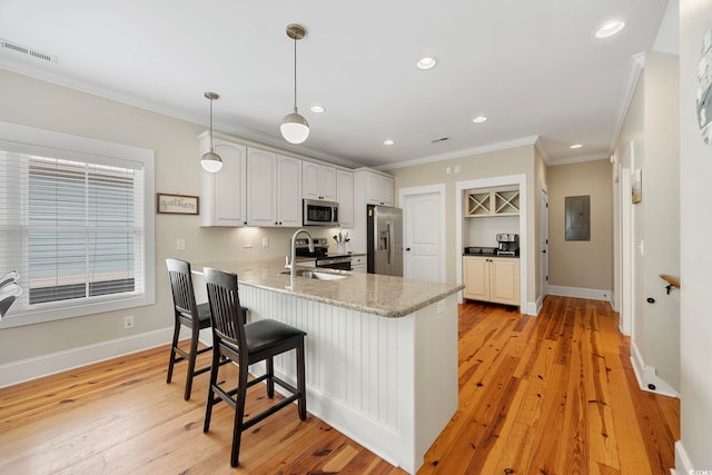 43 Sandlapper Way, Pawleys Island, SC 29585 - kitchen with appliances with stainless steel finishes, a peninsula, ornamental molding, a breakfast bar, and light wood-style flooring