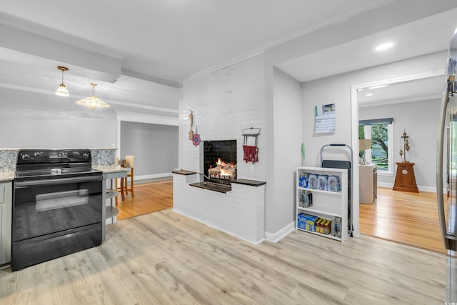 231 Live Oak Ln, Myrtle Beach, SC 29572 - kitchen with black range with electric stovetop, light wood-style flooring, a fireplace, ornamental molding, and pendant lighting