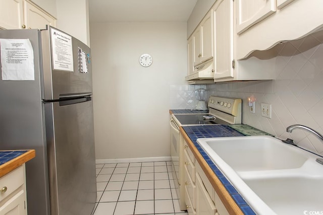 2101 S Ocean Blvd, North Myrtle Beach, SC 29582 - kitchen with freestanding refrigerator, electric range, under cabinet range hood, light tile patterned floors, and white cabinets