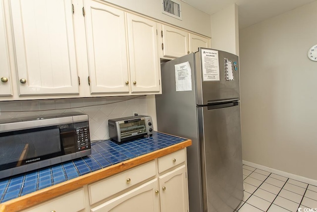2101 S Ocean Blvd, North Myrtle Beach, SC 29582 - kitchen with stainless steel appliances, tile countertops, backsplash, and light tile patterned floors
