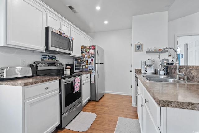 805 Spyderco Rd, Conway, SC 29527 - kitchen with stainless steel appliances, white cabinetry, light wood-style flooring, recessed lighting, and dark countertops