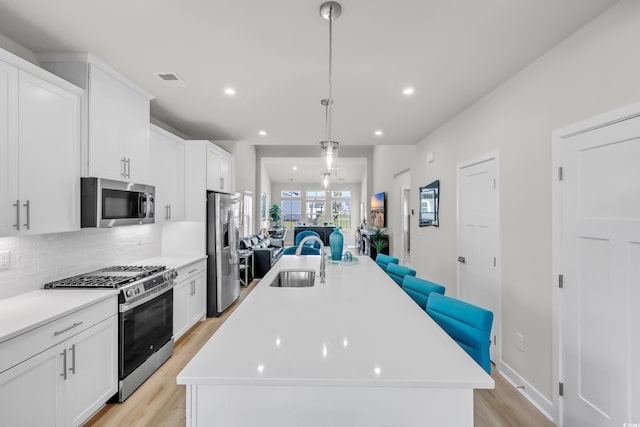 8906 Freya Way Unit 24A, Longs, SC 29568 - kitchen with stainless steel appliances, open floor plan, light wood-style floors, a center island with sink, and backsplash