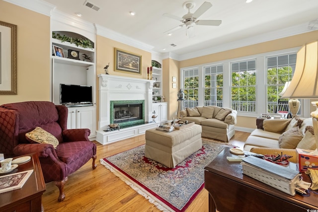 3085 Luvan Blvd, Georgetown, SC 29440 - living area featuring light wood-type flooring, ornamental molding, a ceiling fan, built in shelves, and a fireplace