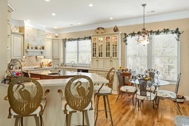 3085 Luvan Blvd, Georgetown, SC 29440 - kitchen with cream cabinetry, a breakfast bar area, light wood-type flooring, pendant lighting, and decorative backsplash