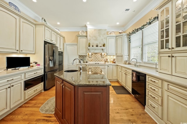 3085 Luvan Blvd, Georgetown, SC 29440 - kitchen with black appliances, cream cabinets, crown molding, an island with sink, and light stone counters