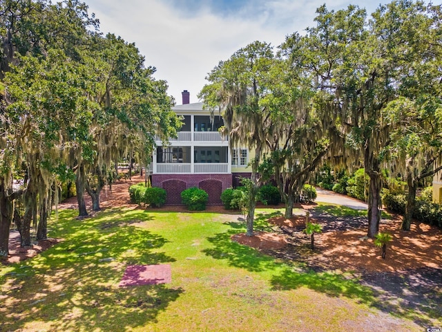 3085 Luvan Blvd, Georgetown, SC 29440 - back of house featuring brick siding, a sunroom, a yard, and a chimney