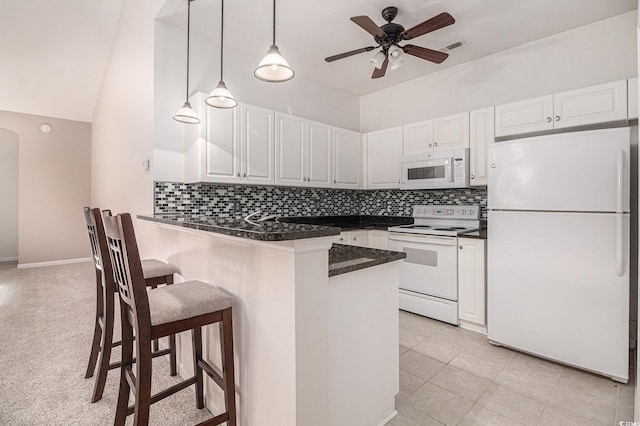 4530 Lighthouse Dr Unit 31-C, Little River, SC 29566 - kitchen with white appliances, dark countertops, white cabinets, a breakfast bar area, and decorative backsplash