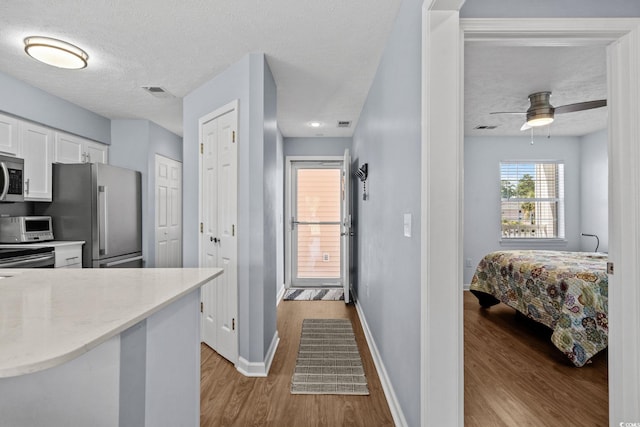 613 Waterway Village Blvd Unit 4-F, Myrtle Beach, SC 29579 - kitchen with appliances with stainless steel finishes, wood finished floors, white cabinets, light stone countertops, and a textured ceiling