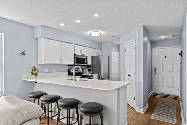 613 Waterway Village Blvd Unit 4-F, Myrtle Beach, SC 29579 - kitchen featuring stainless steel appliances, wood finished floors, a breakfast bar, a textured ceiling, and light countertops