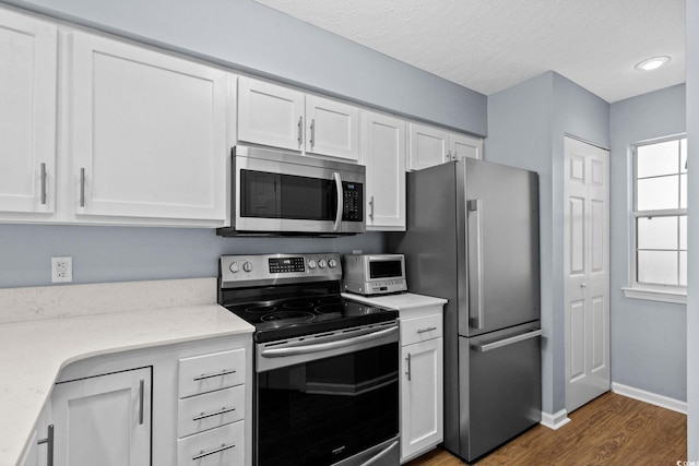 613 Waterway Village Blvd Unit 4-F, Myrtle Beach, SC 29579 - kitchen with stainless steel appliances, white cabinets, wood finished floors, light stone countertops, and a textured ceiling