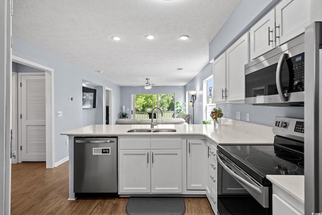 613 Waterway Village Blvd Unit 4-F, Myrtle Beach, SC 29579 - kitchen with appliances with stainless steel finishes, a peninsula, a textured ceiling, wood finished floors, and white cabinets