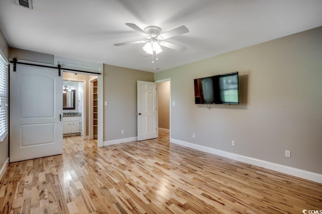414 Dunes Dr, Myrtle Beach, SC 29572 - unfurnished bedroom with light wood finished floors, a barn door, ceiling fan, and connected bathroom
