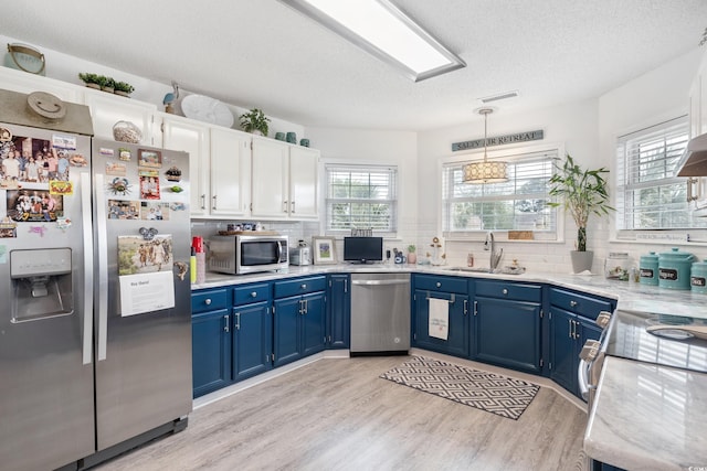 919 Dock Pl, Murrells Inlet, SC 29576 - kitchen with stainless steel appliances, blue cabinets, backsplash, light wood-type flooring, and a textured ceiling
