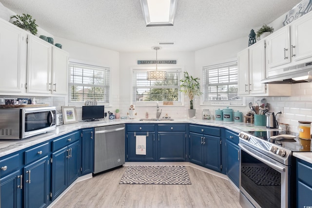 919 Dock Pl, Murrells Inlet, SC 29576 - kitchen with appliances with stainless steel finishes, under cabinet range hood, blue cabinets, plenty of natural light, and a textured ceiling