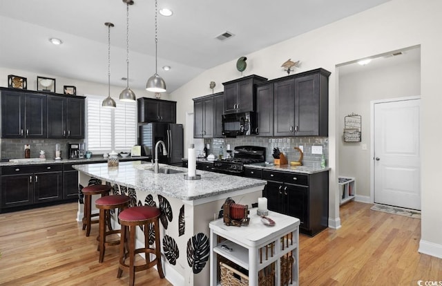 216 Coral Beach Cir, Myrtle Beach, SC 29575 - kitchen featuring black appliances, backsplash, a kitchen island with sink, light wood finished floors, and vaulted ceiling