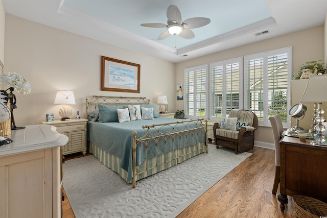 216 Coral Beach Cir, Myrtle Beach, SC 29575 - bedroom with a raised ceiling, light wood-style flooring, multiple windows, a ceiling fan, and crown molding