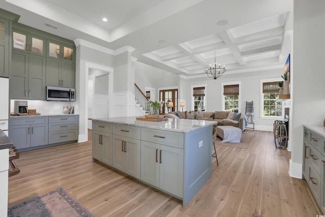 1320 James Island Ave, North Myrtle Beach, SC 29582 - kitchen featuring stainless steel microwave, light wood-style floors, open floor plan, beam ceiling, and a chandelier