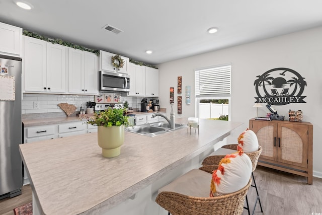 358 Spruce Pine Way, Conway, SC 29526 - kitchen with appliances with stainless steel finishes, a breakfast bar, decorative backsplash, white cabinetry, and light countertops