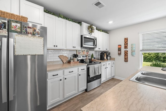 358 Spruce Pine Way, Conway, SC 29526 - kitchen with appliances with stainless steel finishes, light wood-type flooring, tasteful backsplash, light countertops, and white cabinets
