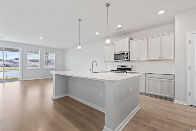 9051 Fort Hill Way, Myrtle Beach, SC 29579 - kitchen featuring appliances with stainless steel finishes, backsplash, light wood finished floors, a kitchen island with sink, and light countertops