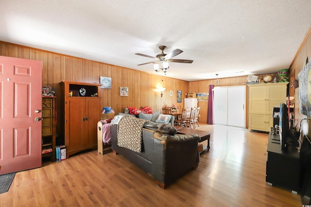 4233 Mica Ave, Little River, SC 29566 - living room with wooden walls, a ceiling fan, light wood-type flooring, and a textured ceiling