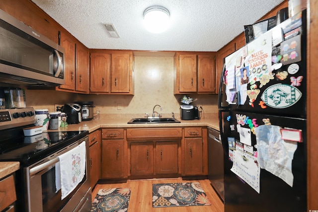4233 Mica Ave, Little River, SC 29566 - kitchen with stainless steel appliances, light countertops, a textured ceiling, light wood-style flooring, and brown cabinets