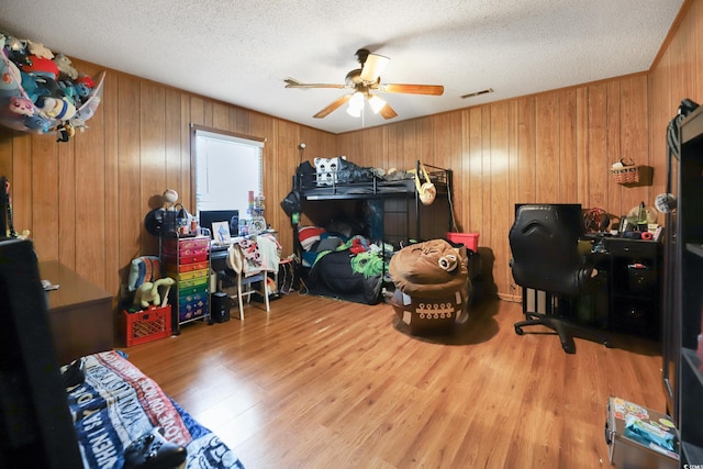 4233 Mica Ave, Little River, SC 29566 - bedroom with wood finished floors, a textured ceiling, wooden walls, and a ceiling fan