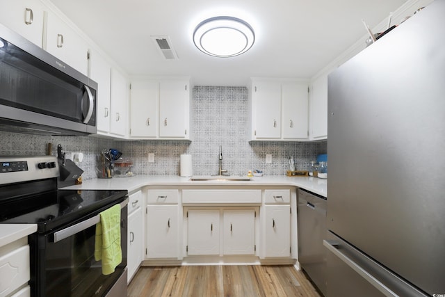 4233 Mica Ave, Little River, SC 29566 - kitchen featuring appliances with stainless steel finishes, decorative backsplash, light countertops, light wood-style floors, and white cabinets