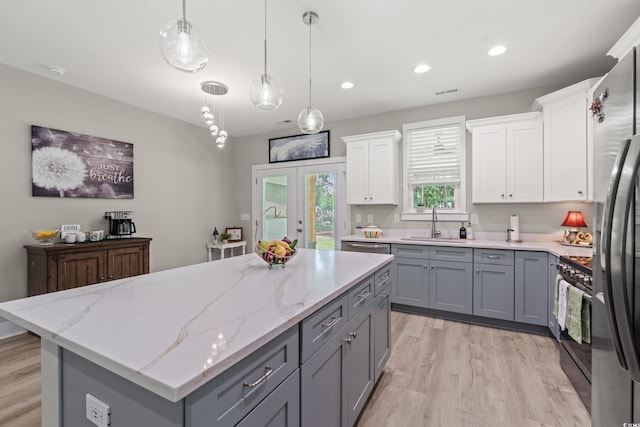 7405 Louisville Rd, Aynor, SC 29511 - kitchen with gray cabinets, black gas stove, a kitchen island, light wood finished floors, and white cabinetry