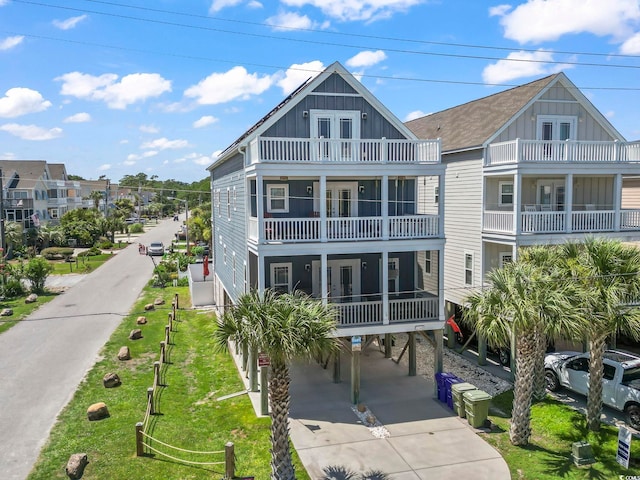 1514-B S Ocean Blvd, Surfside Beach, SC 29575 - back of house with a carport, board and batten siding, a balcony, driveway, and a yard