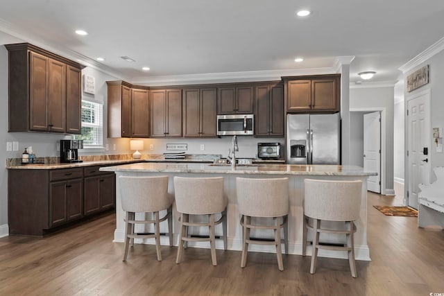 1514-B S Ocean Blvd, Surfside Beach, SC 29575 - kitchen featuring appliances with stainless steel finishes, ornamental molding, a center island with sink, a breakfast bar, and wood finished floors
