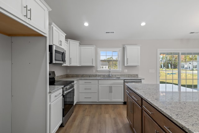 133 Cooper Ln, Georgetown, SC 29440 - kitchen with stainless steel appliances, white cabinetry, wood finished floors, recessed lighting, and light stone counters