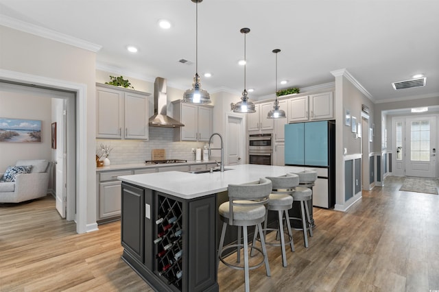 3382 Eversheen Dr, Little River, SC 29566 - kitchen featuring appliances with stainless steel finishes, wall chimney range hood, an island with sink, tasteful backsplash, and ornamental molding