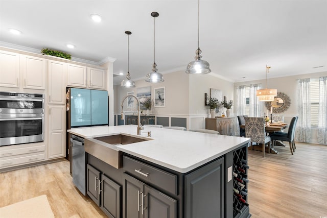 3382 Eversheen Dr, Little River, SC 29566 - kitchen featuring appliances with stainless steel finishes, crown molding, light wood finished floors, a kitchen island with sink, and pendant lighting