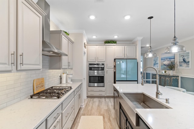 3382 Eversheen Dr, Little River, SC 29566 - kitchen featuring appliances with stainless steel finishes, wall chimney range hood, crown molding, decorative light fixtures, and light wood-type flooring