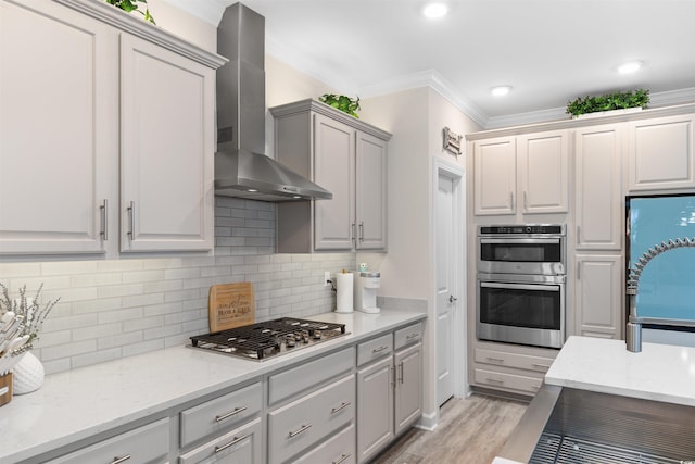 3382 Eversheen Dr, Little River, SC 29566 - kitchen with wall chimney exhaust hood, stainless steel appliances, ornamental molding, light wood finished floors, and decorative backsplash