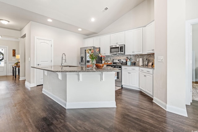756 Culbertson Ave, Myrtle Beach, SC 29577 - kitchen featuring appliances with stainless steel finishes, a center island with sink, decorative backsplash, a breakfast bar, and dark stone counters