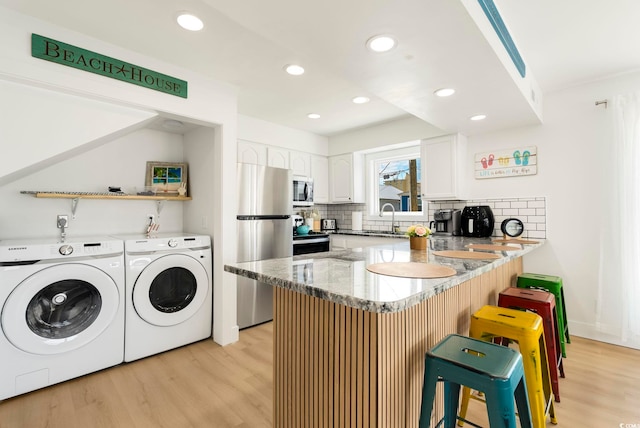 5700 Nixon St, North Myrtle Beach, SC 29582 - kitchen with appliances with stainless steel finishes, a peninsula, stone counters, decorative backsplash, and light wood-type flooring