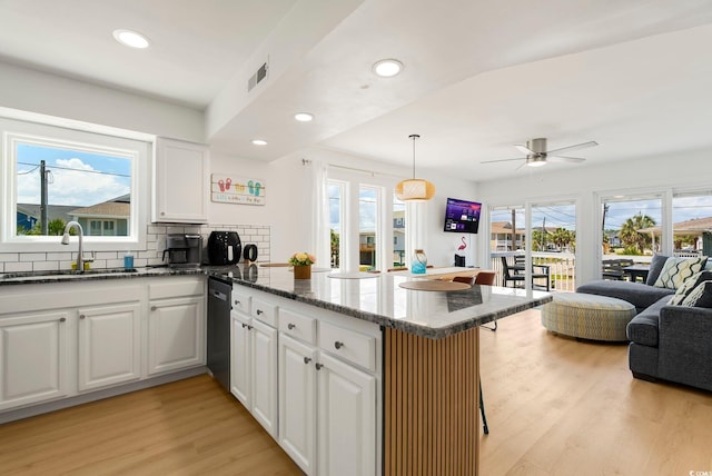 5700 Nixon St, North Myrtle Beach, SC 29582 - kitchen with a peninsula, open floor plan, light wood finished floors, dark stone countertops, and decorative backsplash