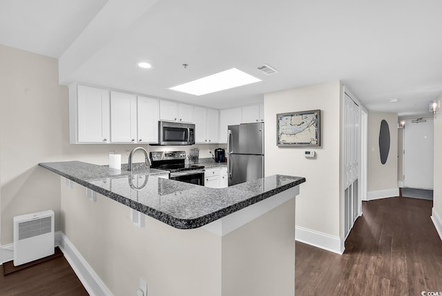 2701 S Ocean Blvd Unit 705, North Myrtle Beach, SC 29582 - kitchen with stainless steel appliances, a peninsula, dark wood-style floors, white cabinetry, and dark stone countertops