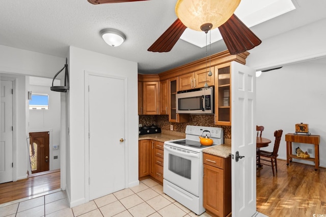 503 Plantation Dr, Surfside Beach, SC 29575 - kitchen featuring electric stove, stainless steel microwave, brown cabinets, and glass insert cabinets
