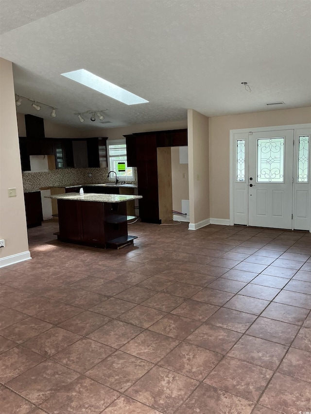983 Nottingham Lakes Rd, Conway, SC 29526 - kitchen with rail lighting, a skylight, a center island, and dark brown cabinetry