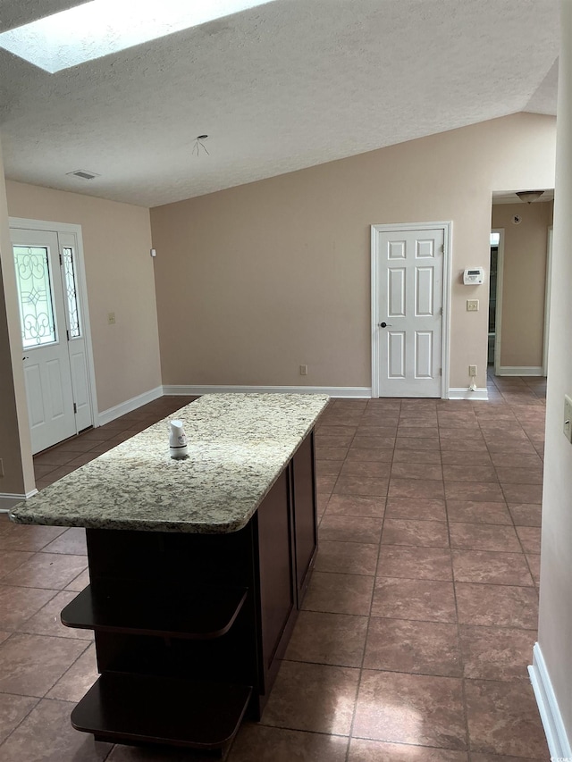 983 Nottingham Lakes Rd, Conway, SC 29526 - kitchen featuring vaulted ceiling, tile patterned floors, a textured ceiling, a kitchen island, and light stone counters
